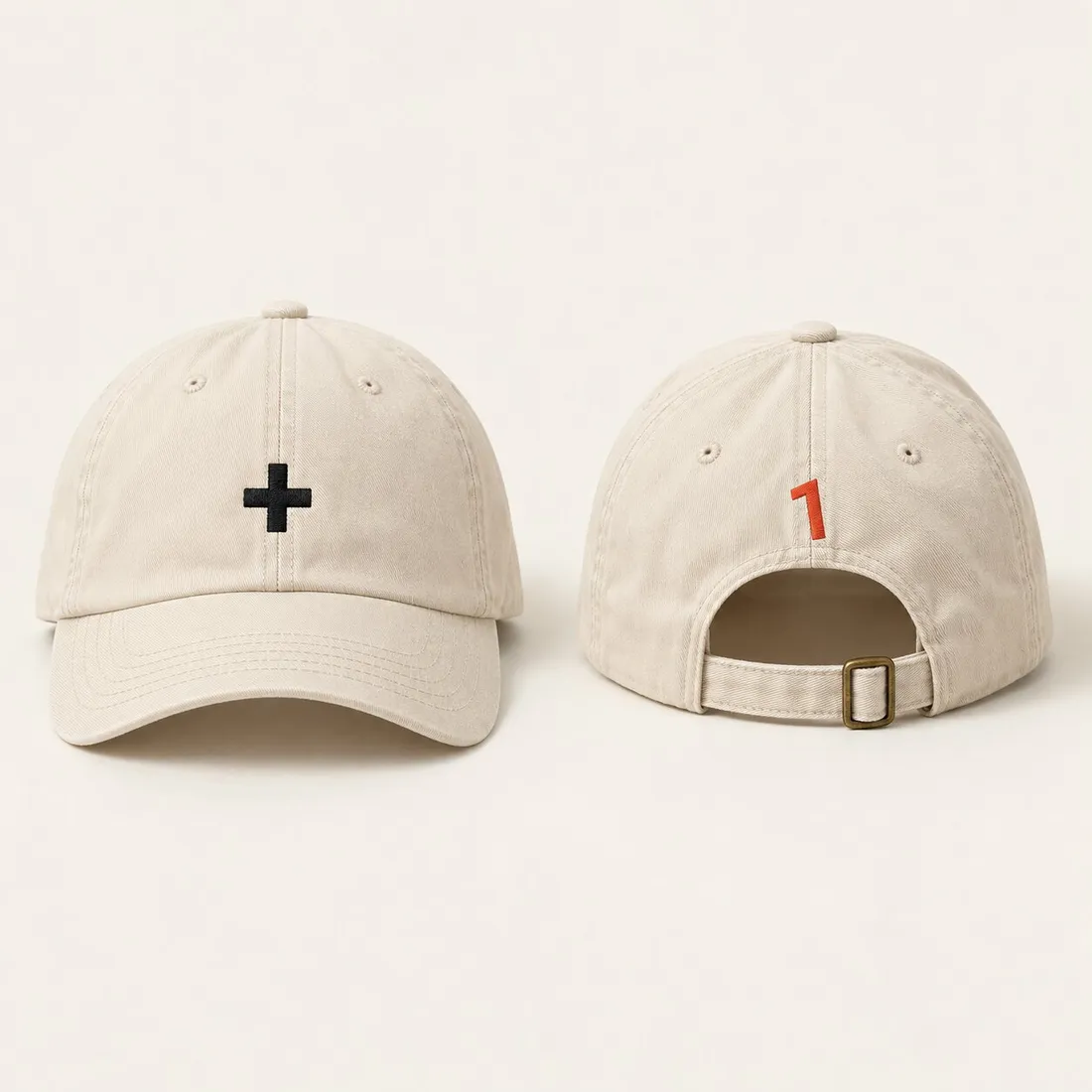 Two ecru caps: one with a small black plus on the front, the other turned round, a small vermilion 1 embroidered above the strap.