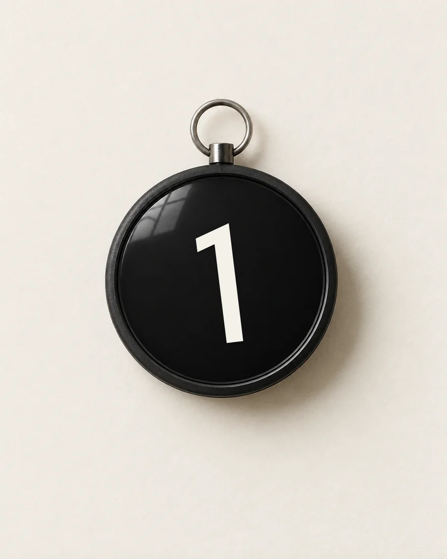 From above: a round black pocket compass, its white needle cut as the leaning 1 and pointing north, so the whole face reads as the disc.