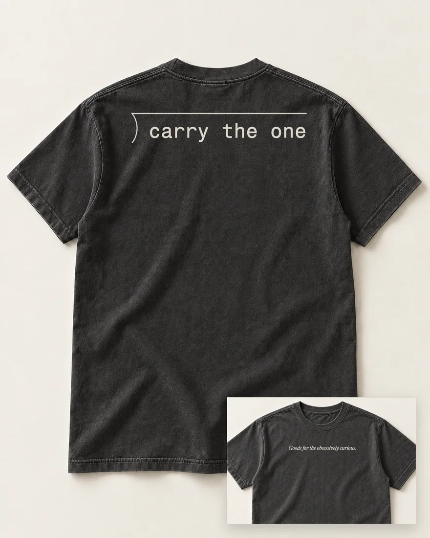 The back of a washed black tee: the long-division bracket, its bar empty, over carry the one. Inset, the front: the motto across the chest.