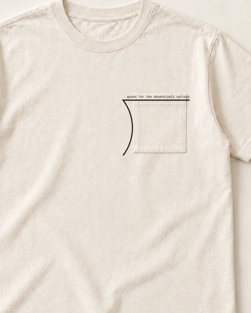An ecru pocket tee: the long-division bracket printed round the chest pocket, its bar along the pocket’s top edge, the motto in small mono on the bar.